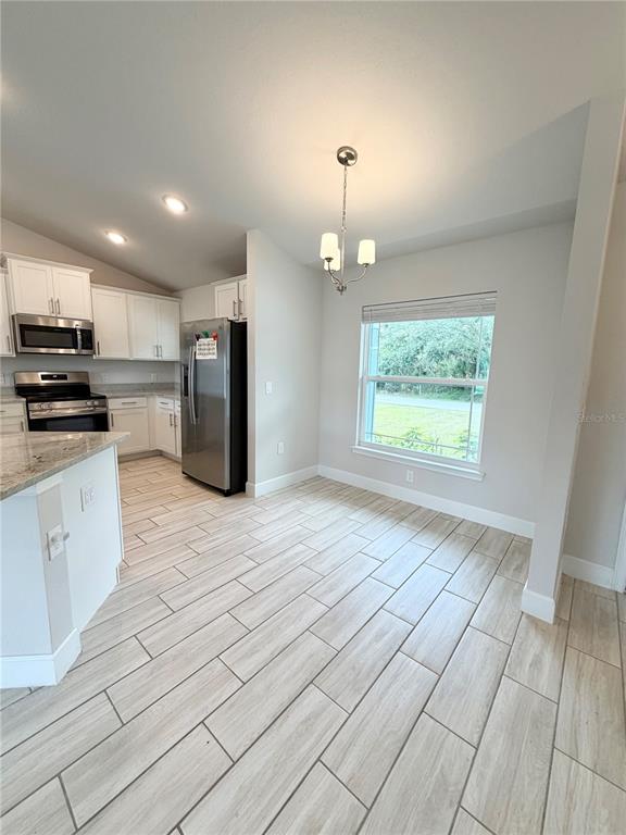 A kitchen and dining area with white cabinets, stainless steel appliances, and light wood-look flooring — 4865 MANILA AVENUE, NORTH PORT, FL