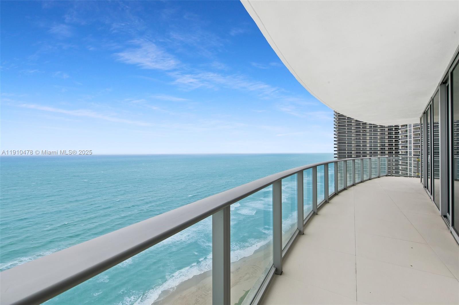 A curved balcony with glass railings overlooks the ocean and a sandy beach — 4111 S Ocean Dr # 3001, Hollywood FL 33019, HOLLYWOOD, FL