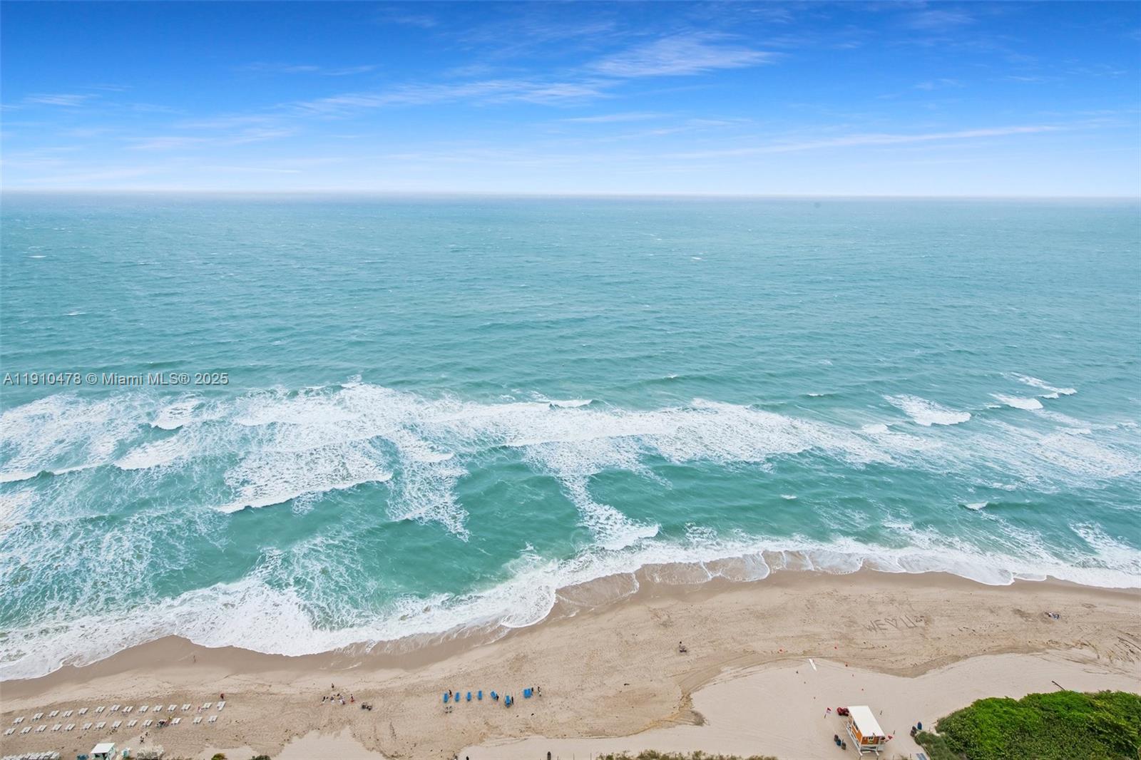 An aerial view shows a sandy beach with crashing waves and a lifeguard tower — 4111 S Ocean Dr # 3001, Hollywood FL 33019, HOLLYWOOD, FL