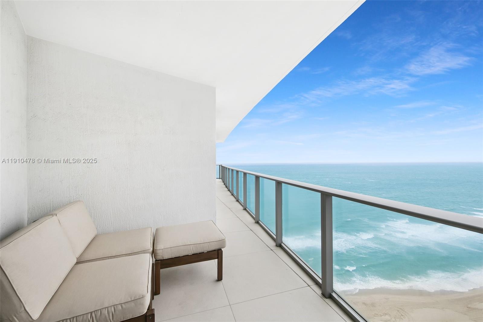 A balcony with a beige sofa and glass railing overlooks the ocean and beach — 4111 S Ocean Dr # 3001, Hollywood FL 33019, HOLLYWOOD, FL