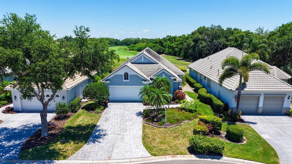 An aerial view shows three suburban houses with tiled roofs and driveways near a golf course — 7823 HERITAGE CLASSIC COURT, LAKEWOOD RANCH, FL