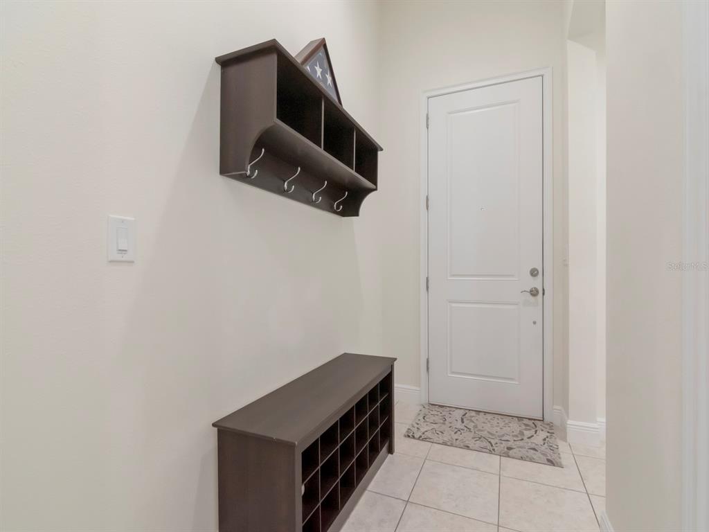 An entryway features a wall-mounted coat rack, a shoe storage bench, and a white door — 8213 SUMMER BROOK COURT, LAND O LAKES, FL