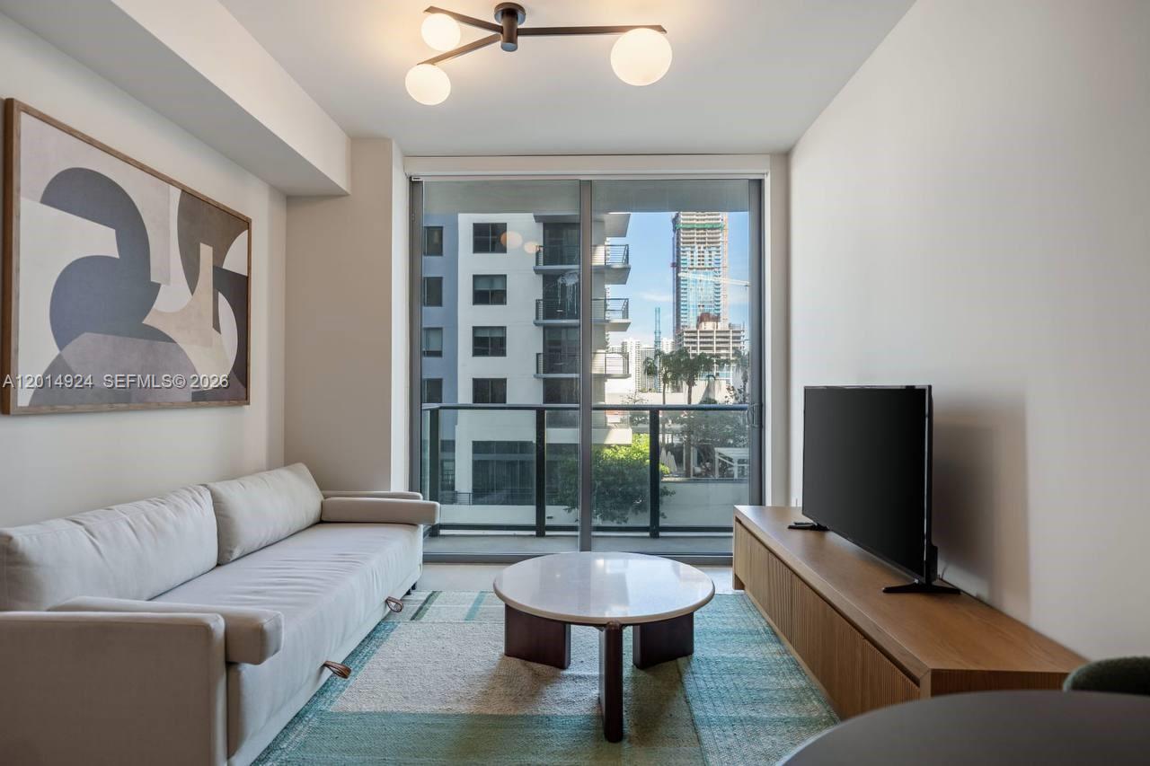 A living room features a light-colored sofa, a round coffee table, and a television console — 11 NE 6th # 1210, Miami FL 33132, MIAMI, FL