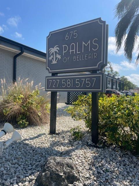 A sign for Palms of Belleair stands in a gravel garden in front of a building — 675 INDIAN ROCKS ROAD N UNIT 106D, BELLEAIR BLUFFS, FL