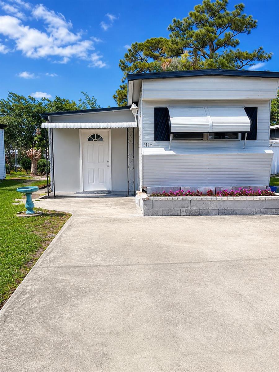 A white mobile home features a concrete driveway, a small porch, and a flower bed — 4149 88th Court S, Boynton Beach FL 33436, BOYNTON BEACH, FL