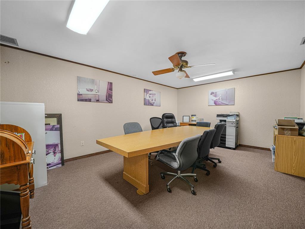 A conference room features a long wooden table, office chairs, and beige carpeted flooring — 112 N POPLAR AVENUE, SANFORD, FL