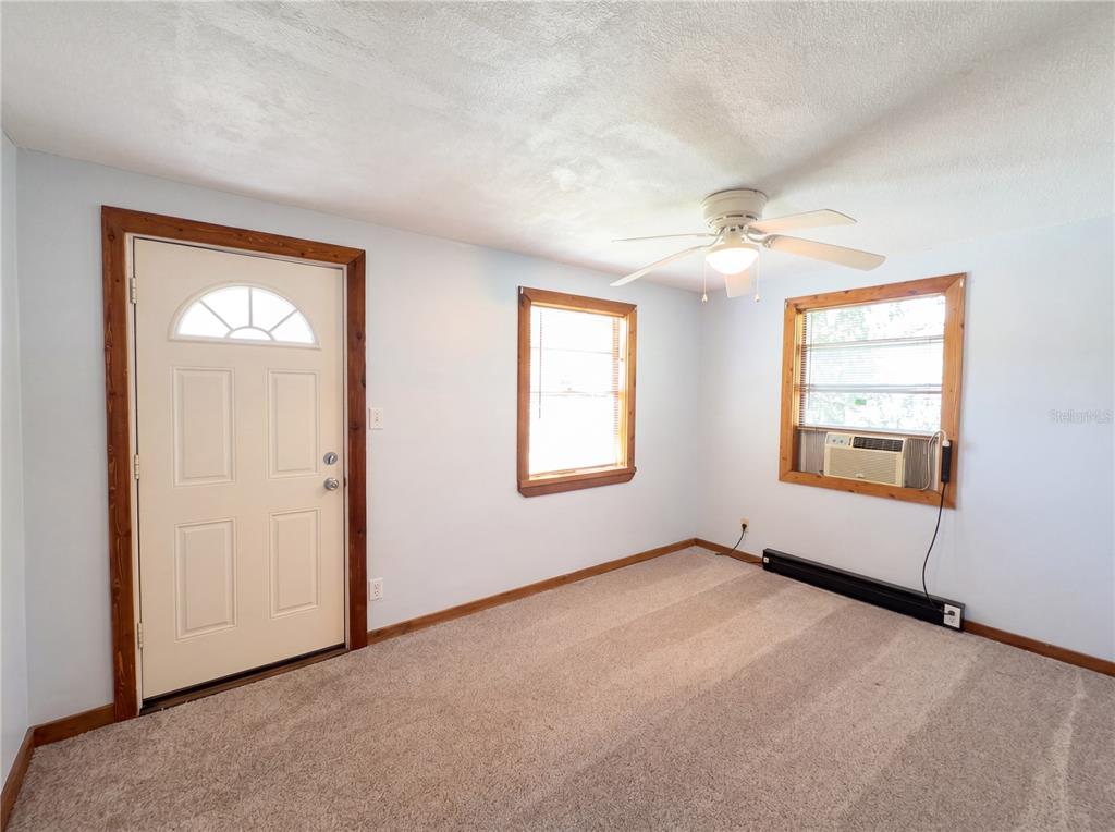 An interior room features light blue walls, beige carpeting, a ceiling fan, and two windows — 1385 BENDER AVENUE, DAYTONA BEACH, FL