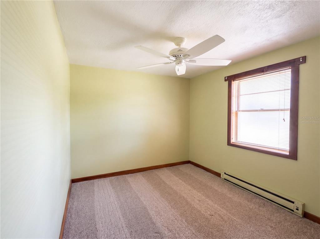 An empty bedroom with light green walls, beige carpet, a ceiling fan, and a window — 1385 BENDER AVENUE, DAYTONA BEACH, FL