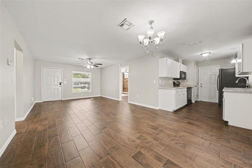 An open-concept living area features wood-look tile flooring, white cabinets, and a ceiling fan — 450 PARK GLEN DRIVE, TAVARES, FL