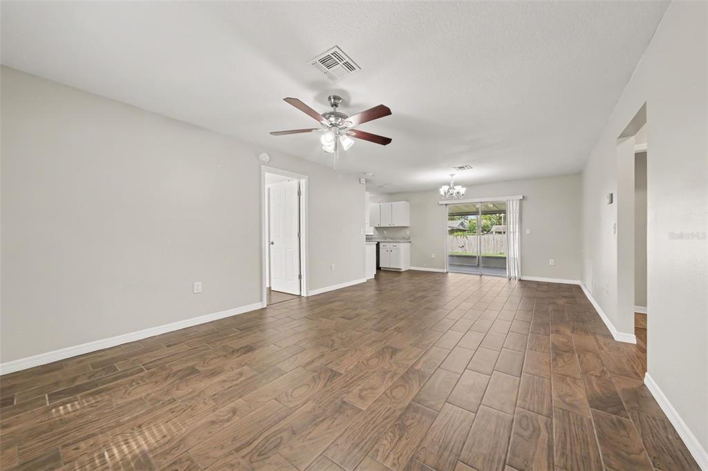 An open-concept living and dining area features wood-look tile flooring and a ceiling fan — 450 PARK GLEN DRIVE, TAVARES, FL