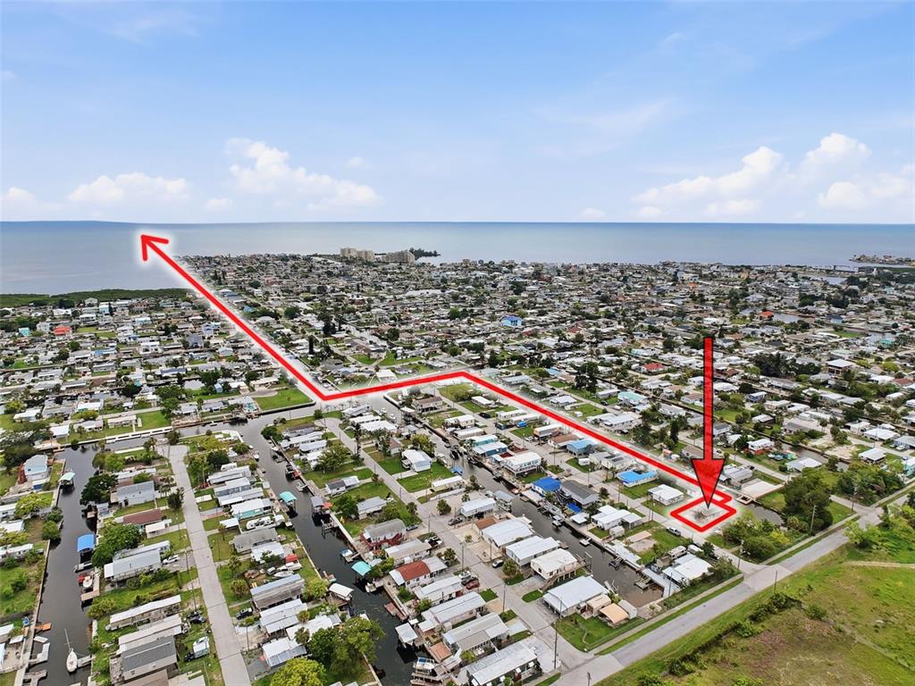 An aerial view shows a residential neighborhood with canals and a highlighted waterfront property — 6839 CURLEW LANE, HUDSON, FL