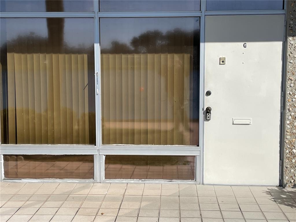 A white door labeled G sits next to large windows with vertical blinds — 4358 TAHITIAN GARDENS CIRCLE UNIT G, HOLIDAY, FL