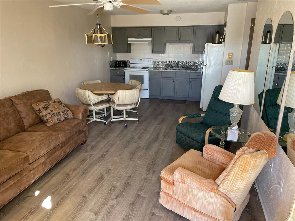 A combined living and dining area features wood-look flooring, gray kitchen cabinets, and multiple armchairs — 4358 TAHITIAN GARDENS CIRCLE UNIT G, HOLIDAY, FL