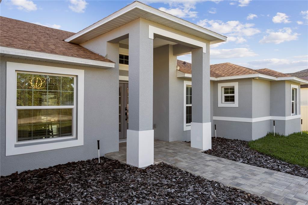 The exterior of a gray single-story house features a covered entryway with white pillars — 1160 NELSON MEADOW LANE, KISSIMMEE, FL
