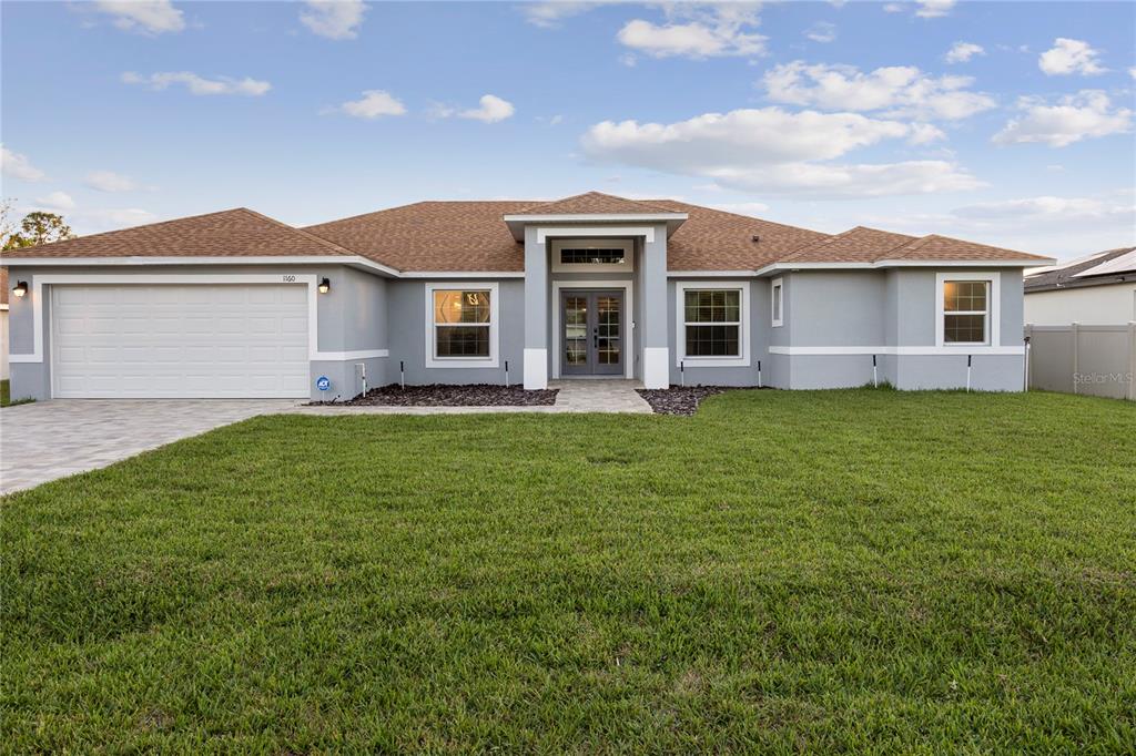 A single-story house with a gray stucco exterior, a two-car garage, and a brown roof — 1160 NELSON MEADOW LANE, KISSIMMEE, FL