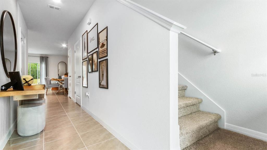 A hallway with a console table, wall art, and carpeted stairs leading to an upper level — 441 WARM HERON PLACE, RUSKIN, FL