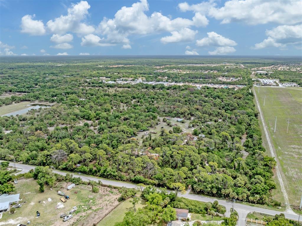 An aerial view shows a wooded lot bordered by a road and a grassy field — 400 S HAVANA ROAD, VENICE, FL