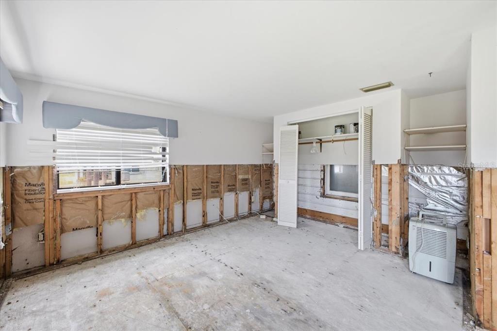 An unfinished bedroom with exposed wall studs, fiberglass insulation, and a concrete subfloor — 4436 106TH STREET W, BRADENTON, FL