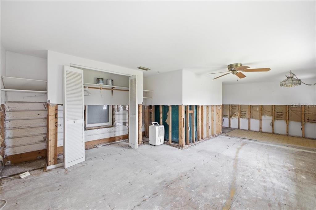 An unfinished room features exposed wall studs, removed drywall, a ceiling fan, and a closet — 4436 106TH STREET W, BRADENTON, FL