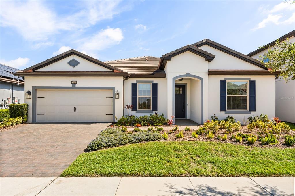 A single-story house with a white stucco exterior, blue shutters, and a two-car garage — 7916 WANDERING WAY, ORLANDO, FL
