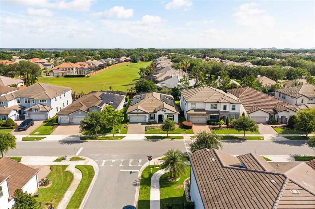 An aerial view shows a suburban neighborhood with houses, driveways, and a large grassy field — 7916 WANDERING WAY, ORLANDO, FL