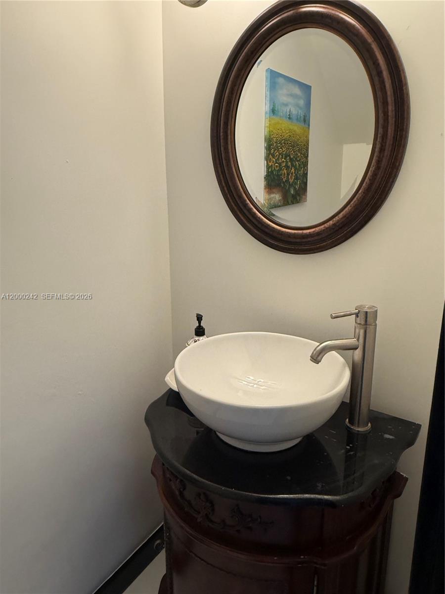 A bathroom features a vessel sink on a dark vanity with an oval wall mirror — 13505 NE 23rd Ct, North Miami FL 33181, NORTH MIAMI, FL