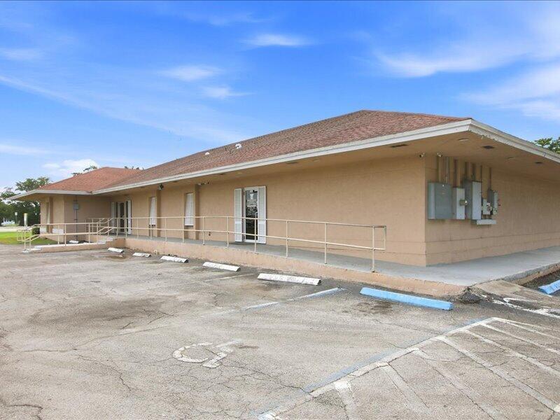 A tan, single-story commercial building with a wheelchair ramp and an asphalt parking lot — 1100 S Main Street, Belle Glade FL 33430, BELLE GLADE, FL