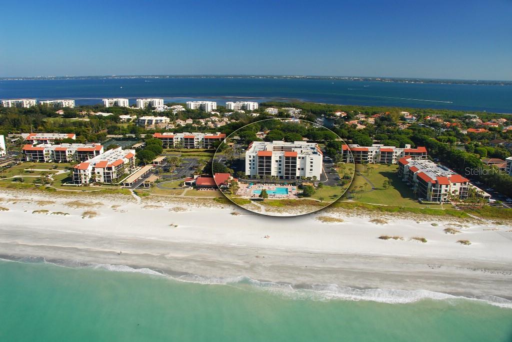 An open-concept living and dining area features tile floors, a glass table, and a balcony — 1945 GULF OF MEXICO DRIVE UNIT M2-402, LONGBOAT KEY, FL