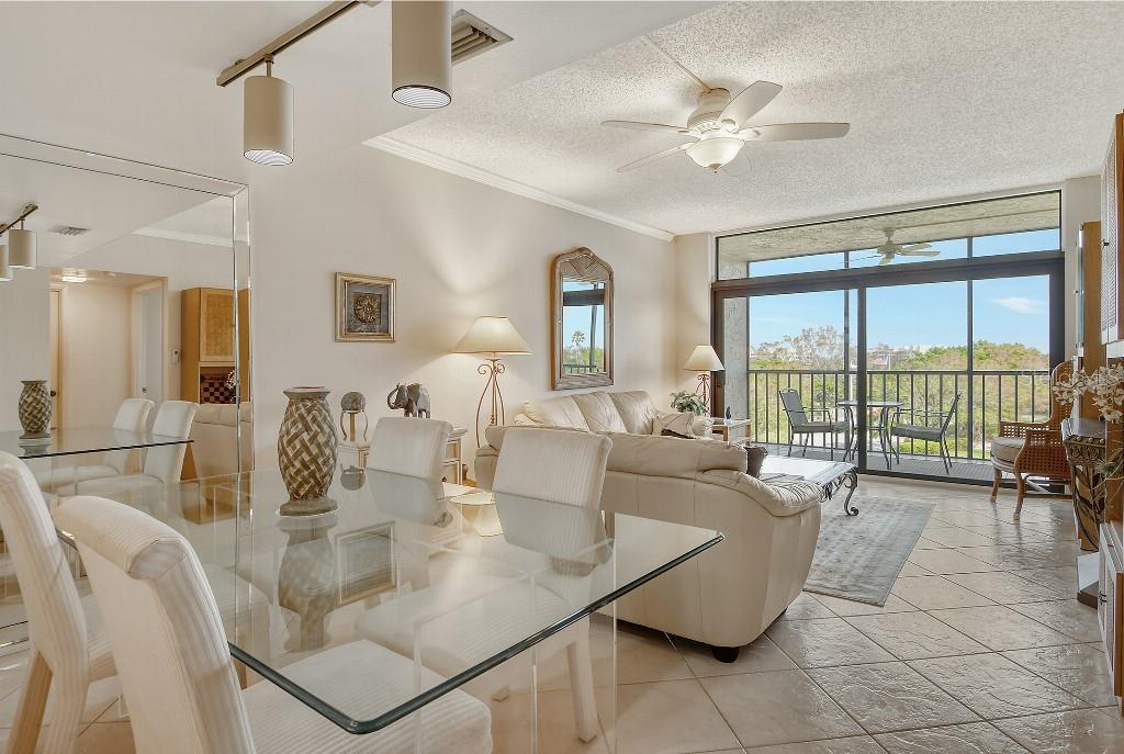 A view from a white kitchen into a living area with tile floors and balcony access — 1945 GULF OF MEXICO DRIVE UNIT M2-402, LONGBOAT KEY, FL