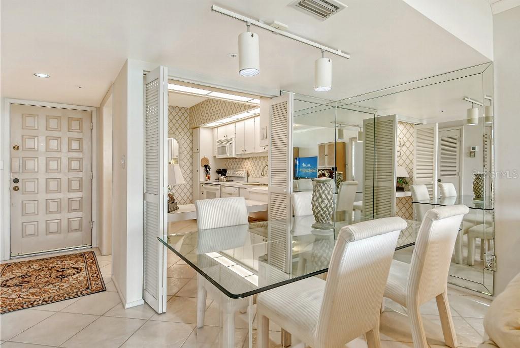 A galley kitchen features white cabinets, white appliances, a tiled backsplash, and a wall mirror — 1945 GULF OF MEXICO DRIVE UNIT M2-402, LONGBOAT KEY, FL
