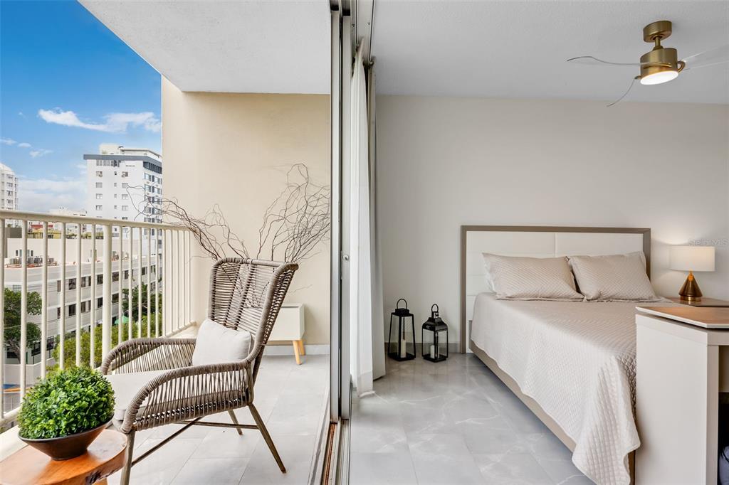 A bedroom with a bed and balcony featuring a wicker chair and city views — 1477 ASHFORD UNIT 608, SAN JUAN, PR