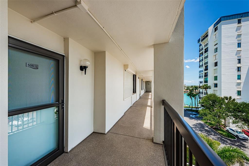 An outdoor balcony walkway features a door labeled 505, concrete flooring, and a metal railing — 9525 BLIND PASS ROAD UNIT 505, ST PETE BEACH, FL
