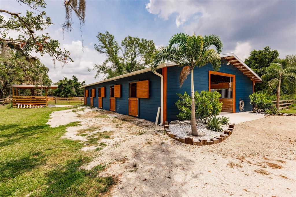 A blue barn with wooden stall doors and a palm tree sits on a grassy lot — 9325 SW LIPE ROAD, ARCADIA, FL