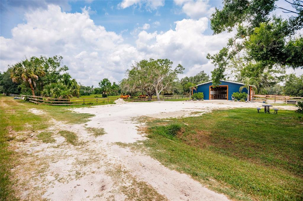 A blue barn sits on a sandy lot surrounded by green grass and trees — 9325 SW LIPE ROAD, ARCADIA, FL