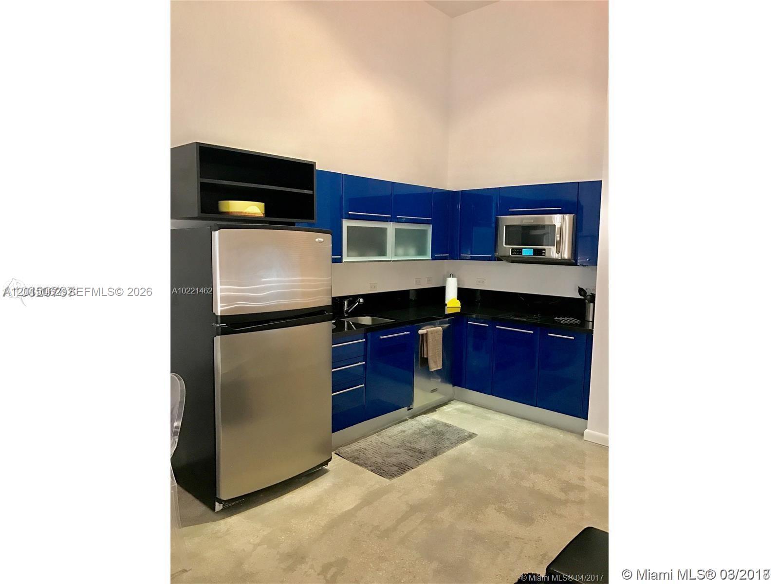 A kitchen features blue high-gloss cabinets, stainless steel appliances, and black countertops — 253 NE 2nd St # 312, Miami FL 33132, MIAMI, FL