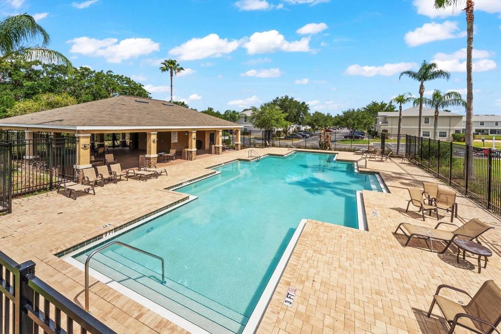 An outdoor swimming pool with a covered patio area and lounge chairs on a paved deck — 774 ASHENTREE DRIVE, PLANT CITY, FL