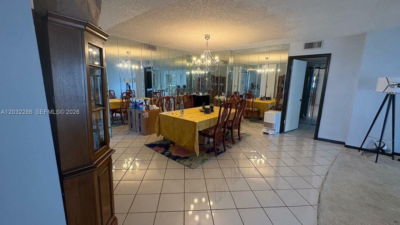 A dining room features a yellow-clothed table, tiled floors, and a wall of mirrors — 1865 S Ocean Dr # 12E, Hallandale Beach FL 33009, HALLANDALE BEACH, FL