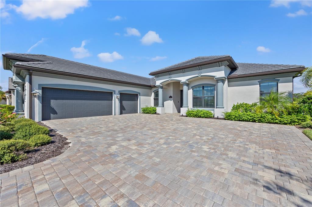 A single-story house with a paved driveway, a three-car garage, and a tiled roof — 5623 MULLIGAN WAY, LAKEWOOD RANCH, FL
