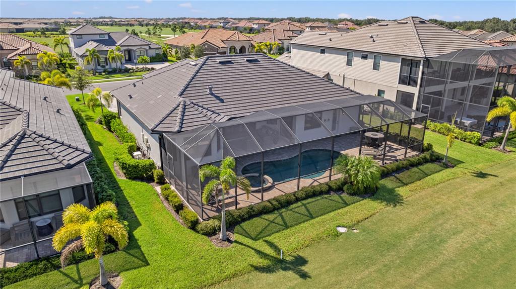 An aerial view of a suburban house with a screened-in pool and backyard lawn — 5623 MULLIGAN WAY, LAKEWOOD RANCH, FL