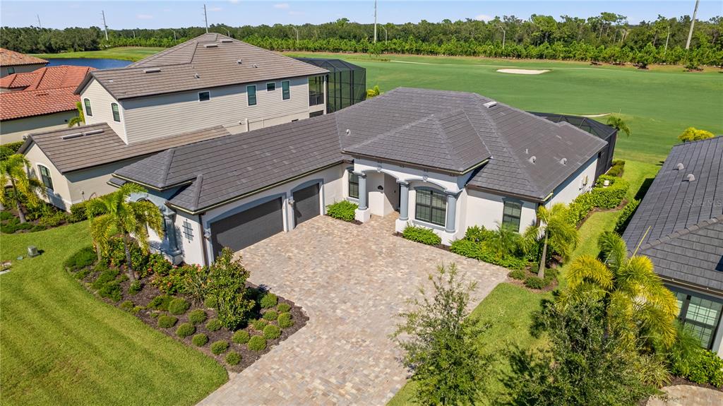 An aerial view of a single-story house with a paver driveway and a golf course — 5623 MULLIGAN WAY, LAKEWOOD RANCH, FL