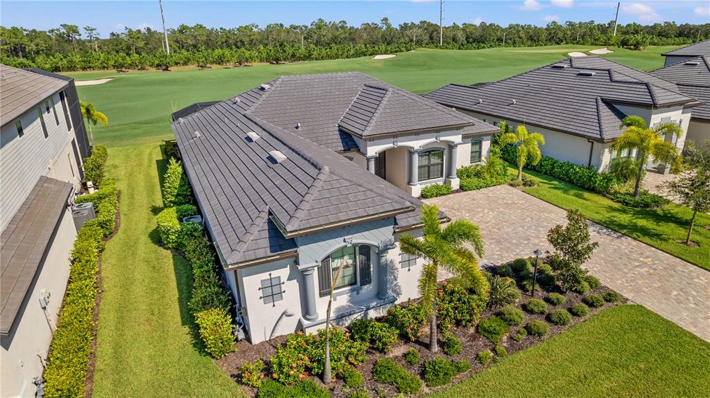 An aerial view of a single-story house with a tiled roof and a paved driveway — 5623 MULLIGAN WAY, LAKEWOOD RANCH, FL