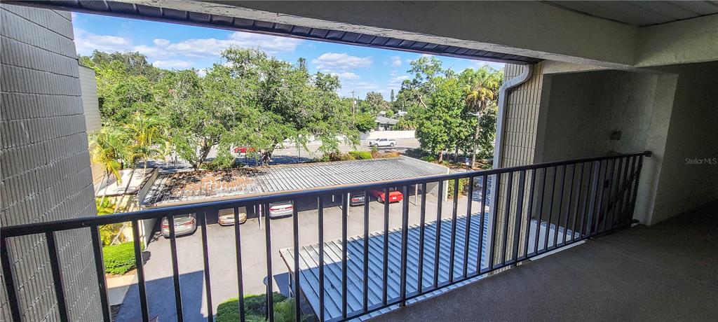 An elevated balcony overlooks a parking lot with covered carports and surrounding trees — 2749 ORCHID OAKS DRIVE UNIT 302, SARASOTA, FL