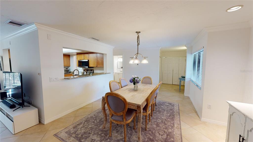 A dining room with a wooden table, six chairs, and a pass-through to the kitchen — 2749 ORCHID OAKS DRIVE UNIT 302, SARASOTA, FL