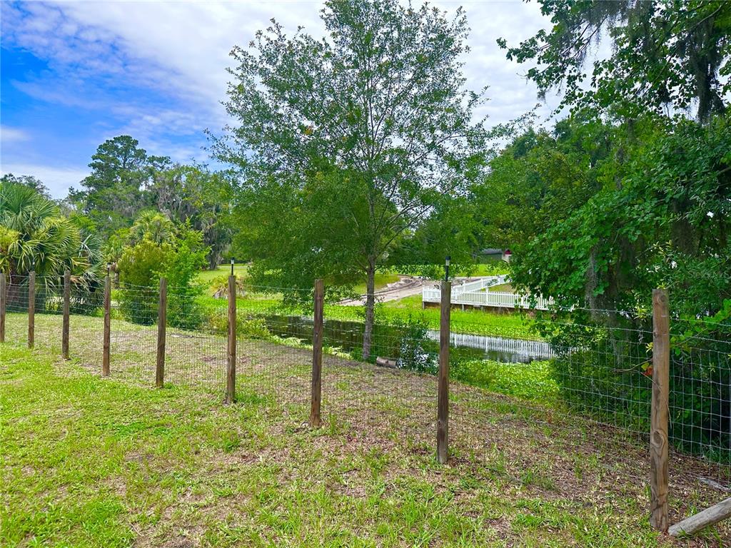 A wire fence runs across a grassy yard overlooking a small pond and trees — 000 SE 197TH PLACE, INGLIS, FL