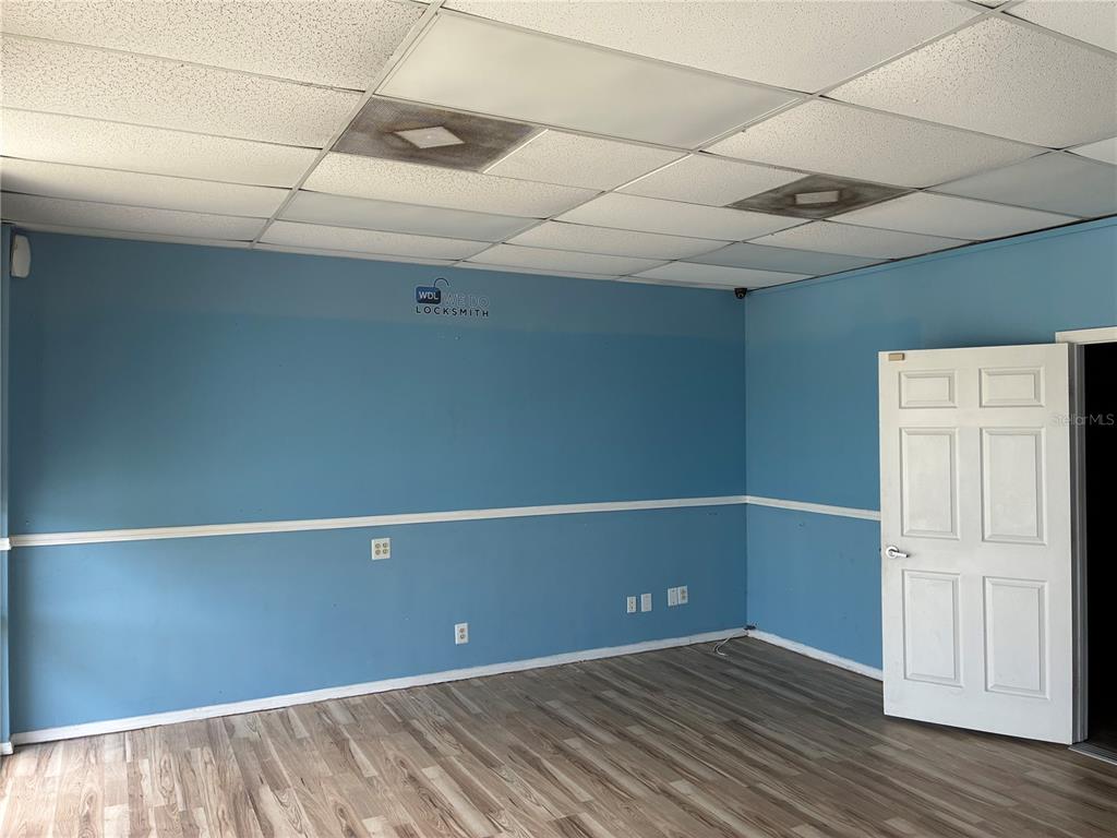 An empty room features blue walls with white trim, a drop ceiling, and wood-look flooring — 2911 39TH STREET UNIT 200, ORLANDO, FL