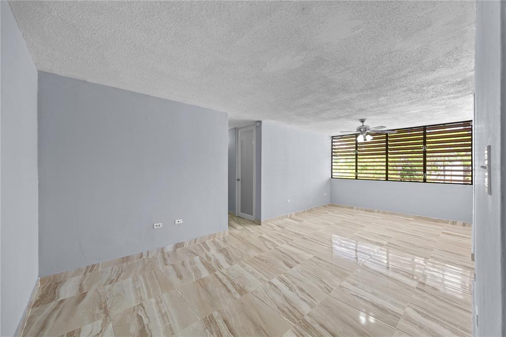An empty room with light blue walls, marble-patterned tile floors, and a ceiling fan — 3015 ALMONTE ST. COND. GUARIONEX APT. 304, SAN JUAN, PR