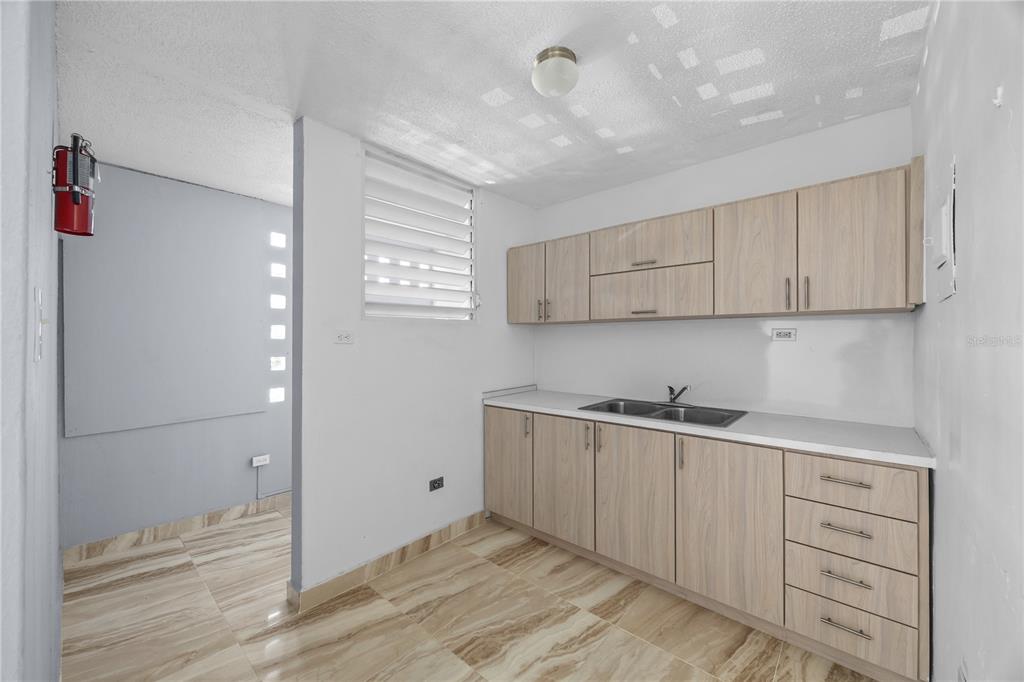 A kitchen features light wood cabinets, a stainless steel sink, and beige marble-patterned tile floors — 3015 ALMONTE ST. COND. GUARIONEX APT. 304, SAN JUAN, PR