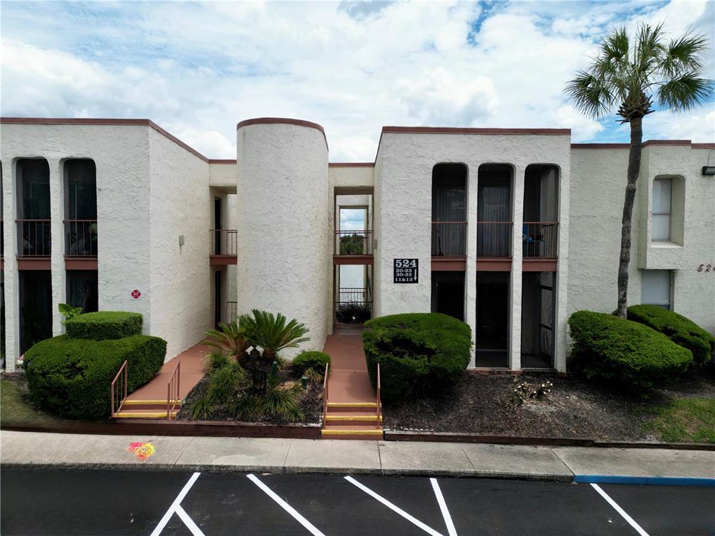 Exterior view of a two-story apartment building with stucco walls and a central walkway — 524 ORANGE DRIVE UNIT 11, ALTAMONTE SPRINGS, FL