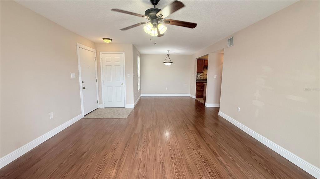An open-concept living and dining area features wood-look flooring, a ceiling fan, and neutral walls — 524 ORANGE DRIVE UNIT 11, ALTAMONTE SPRINGS, FL
