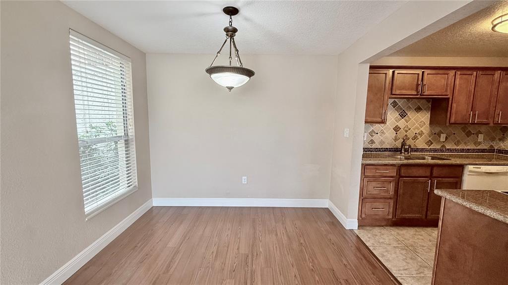 A dining area with wood-look flooring and a pendant light next to a kitchen — 524 ORANGE DRIVE UNIT 11, ALTAMONTE SPRINGS, FL